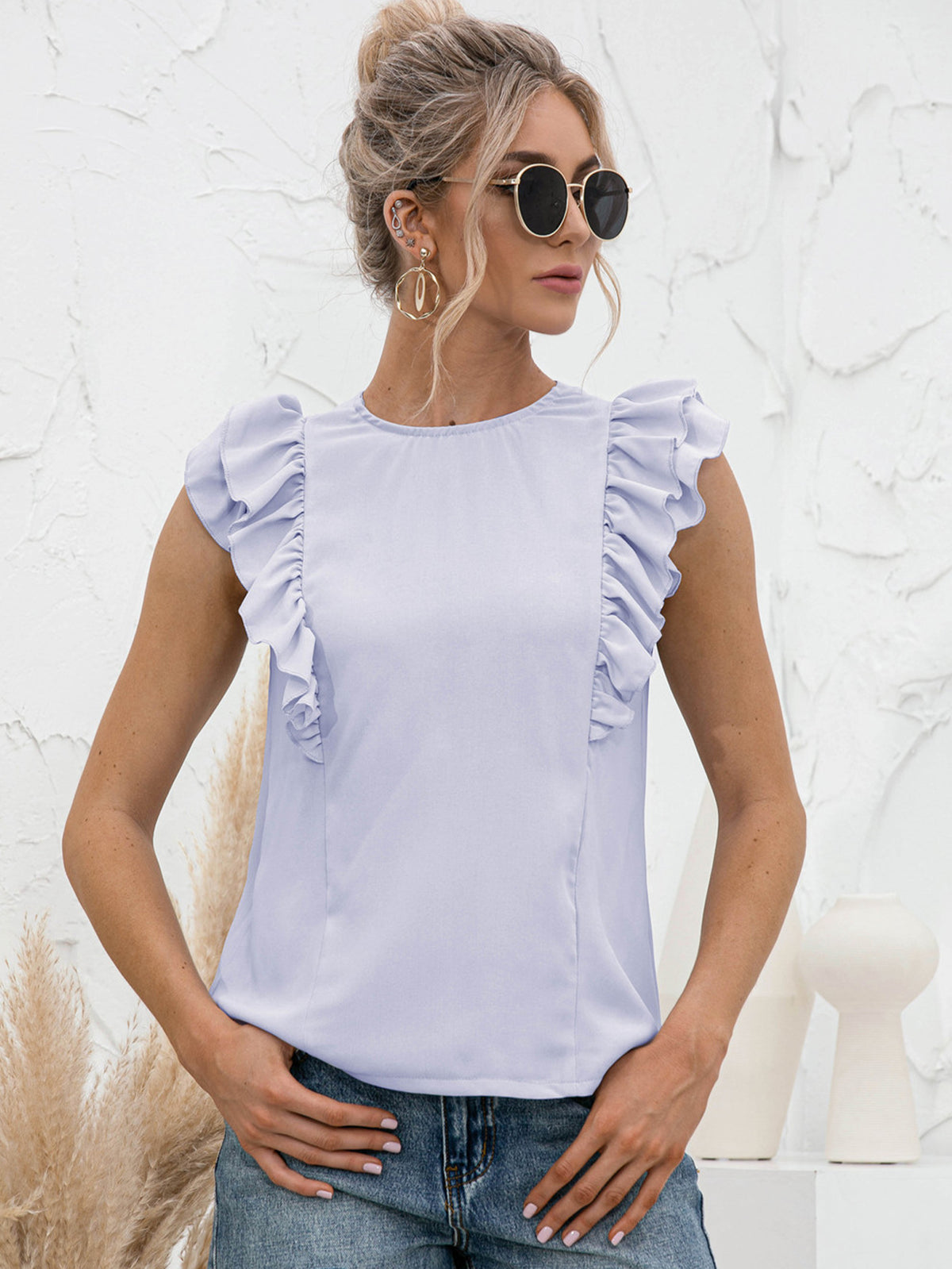 Light blue ruffled yoke sleeveless blouse with a round neckline.