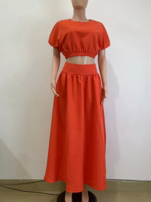 Orange crop top with puff sleeves and elastic hem, paired with a high-waisted maxi skirt.