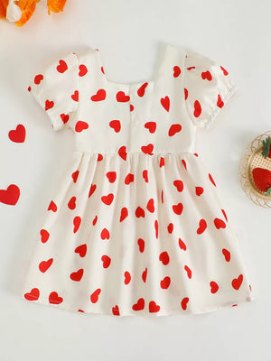 Baby girls white cotton dress with red hearts, puff sleeves, and square neckline.