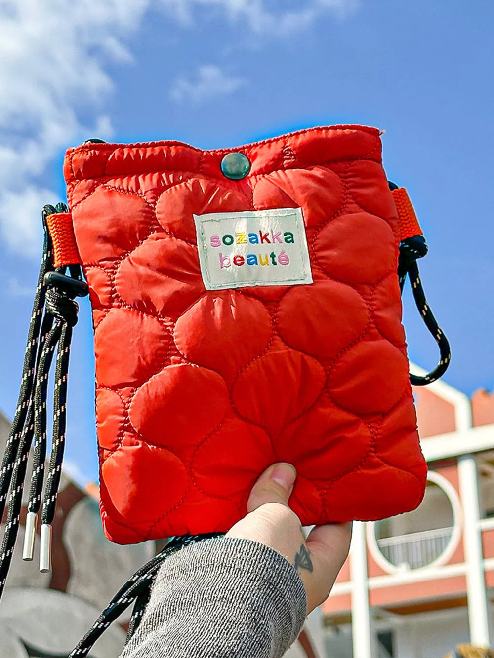 Red quilted mini crossbody bag with circular pattern and adjustable strap.