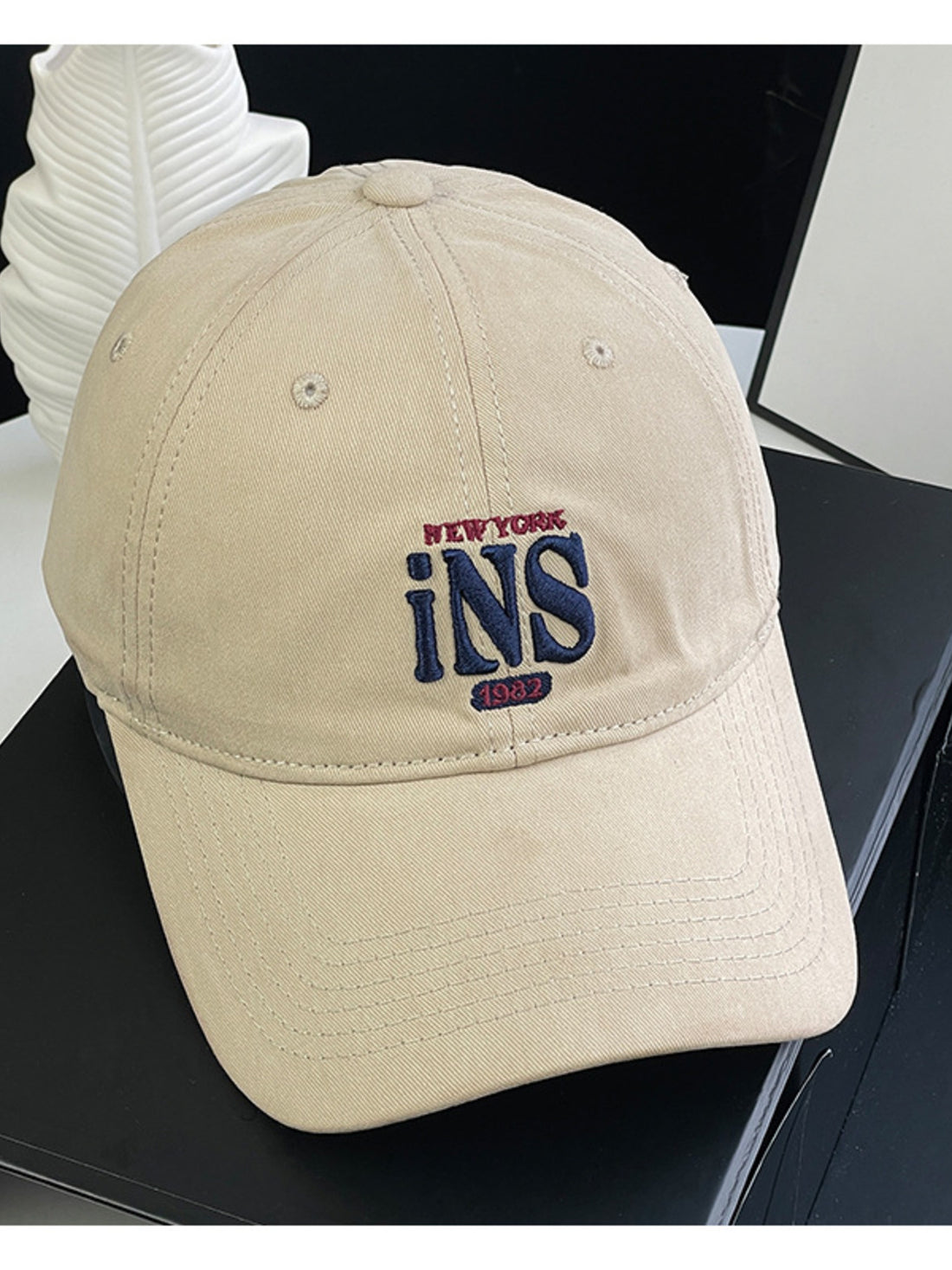 Tan baseball cap with embroidered New York INS 1982 logo.