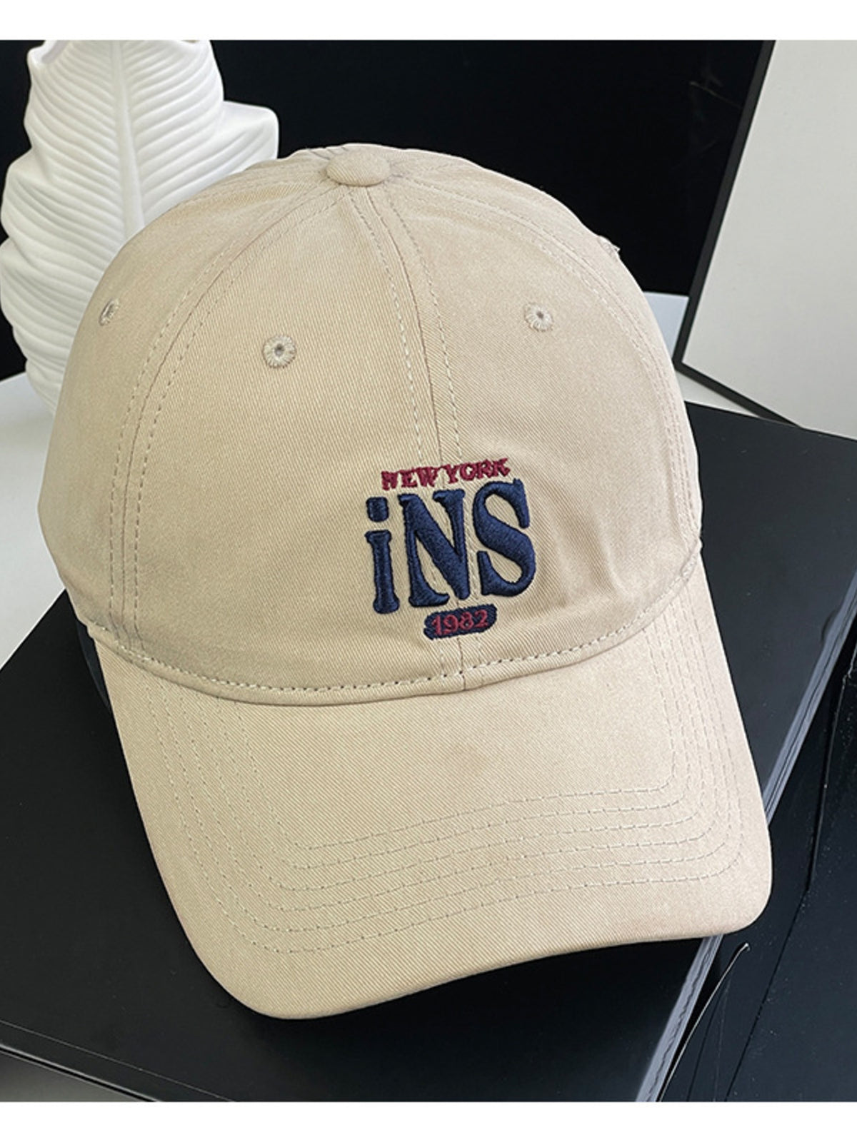 Tan baseball cap with embroidered New York INS 1982 logo.