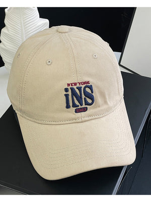 Tan baseball cap with embroidered New York INS 1982 logo.