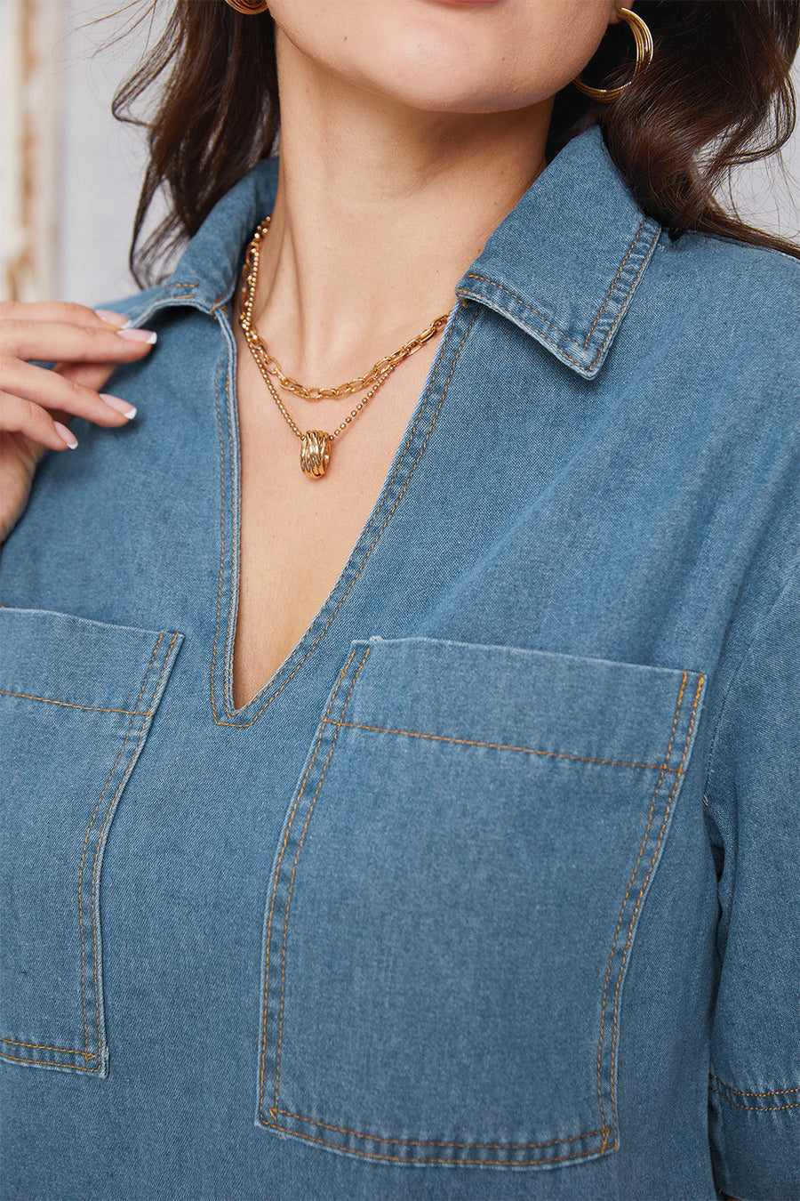Denim mini dress in medium wash with plunging collar and chest pockets.