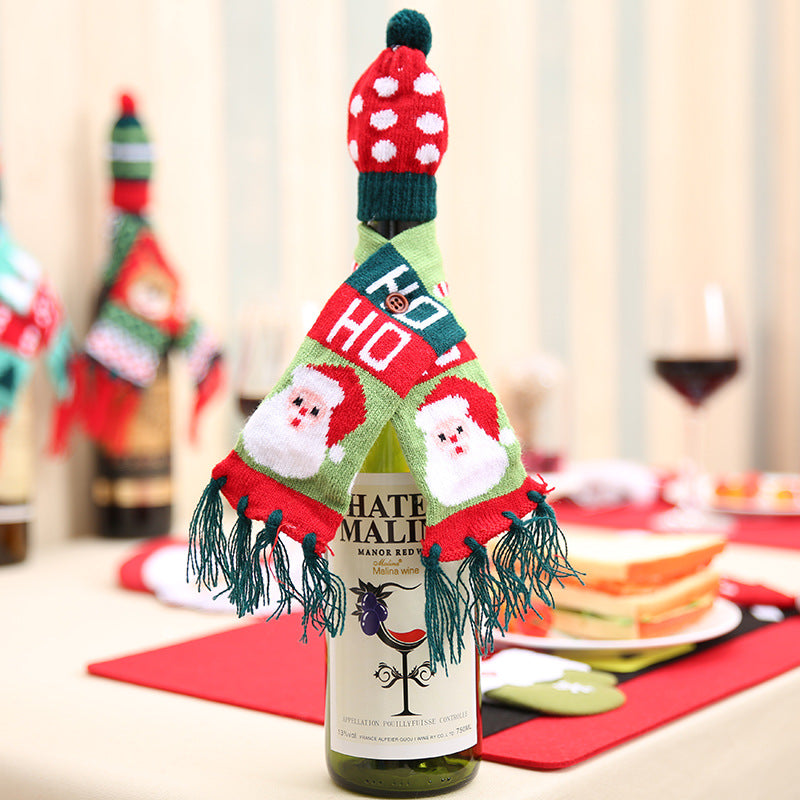 Holiday knit bottle cosy with Santa and "HO HO" text, red polka dot hat and green fringe scarf.