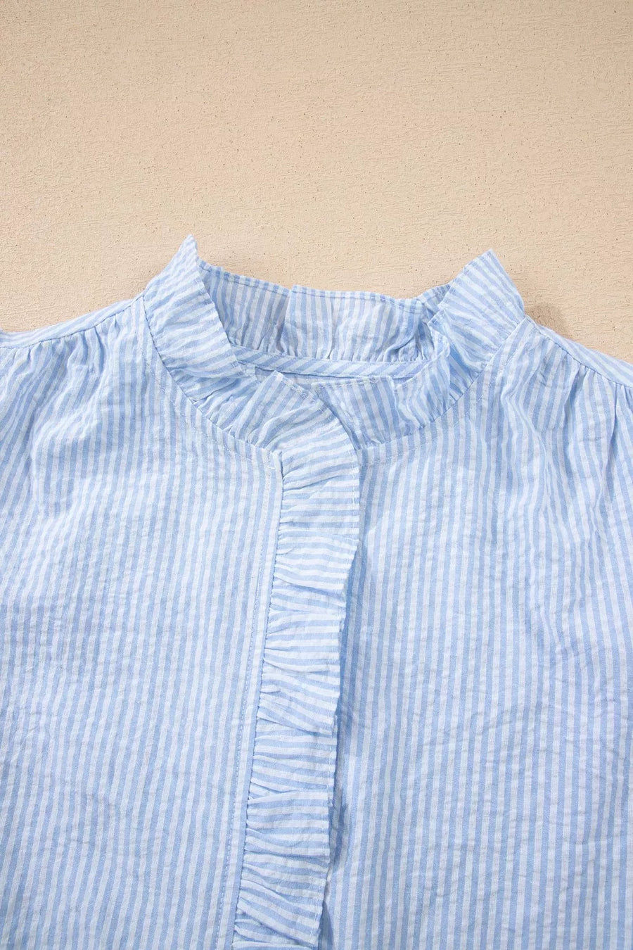 Blue striped cotton shirt with ruffled neckline and placket detail.