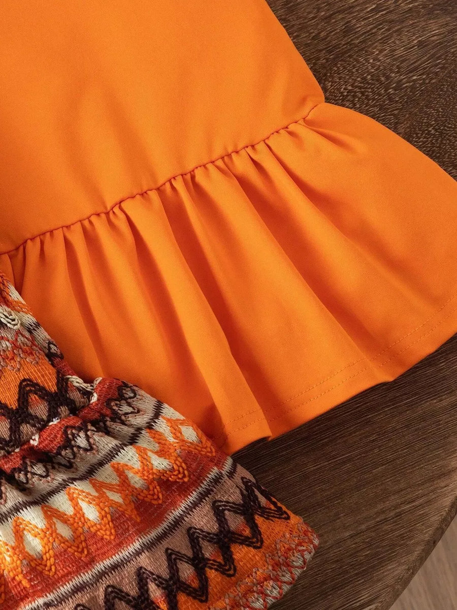 Orange baby halter dress with ruffled hem and patterned trim