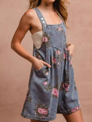 Denim overalls with pink floral print, button straps, and pocket details.