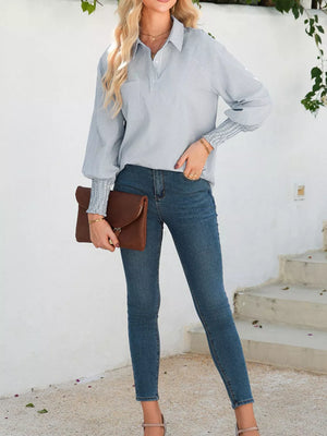 Blue pinstripe collared shirt with cinched cuffs and balloon sleeves, paired with skinny jeans.