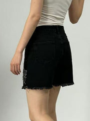Black denim shorts with rhinestone embellishments and frayed hem.