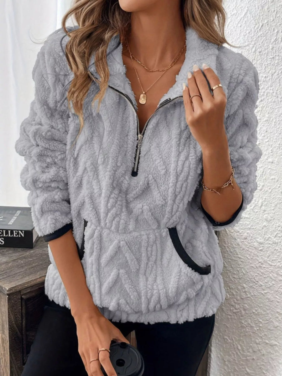 Light gray sherpa half zip sweatshirt with chevron texture and black trim pocket detail.