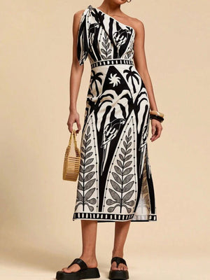 Black and white tropical print one-shoulder midi dress with defined waist and side slits.