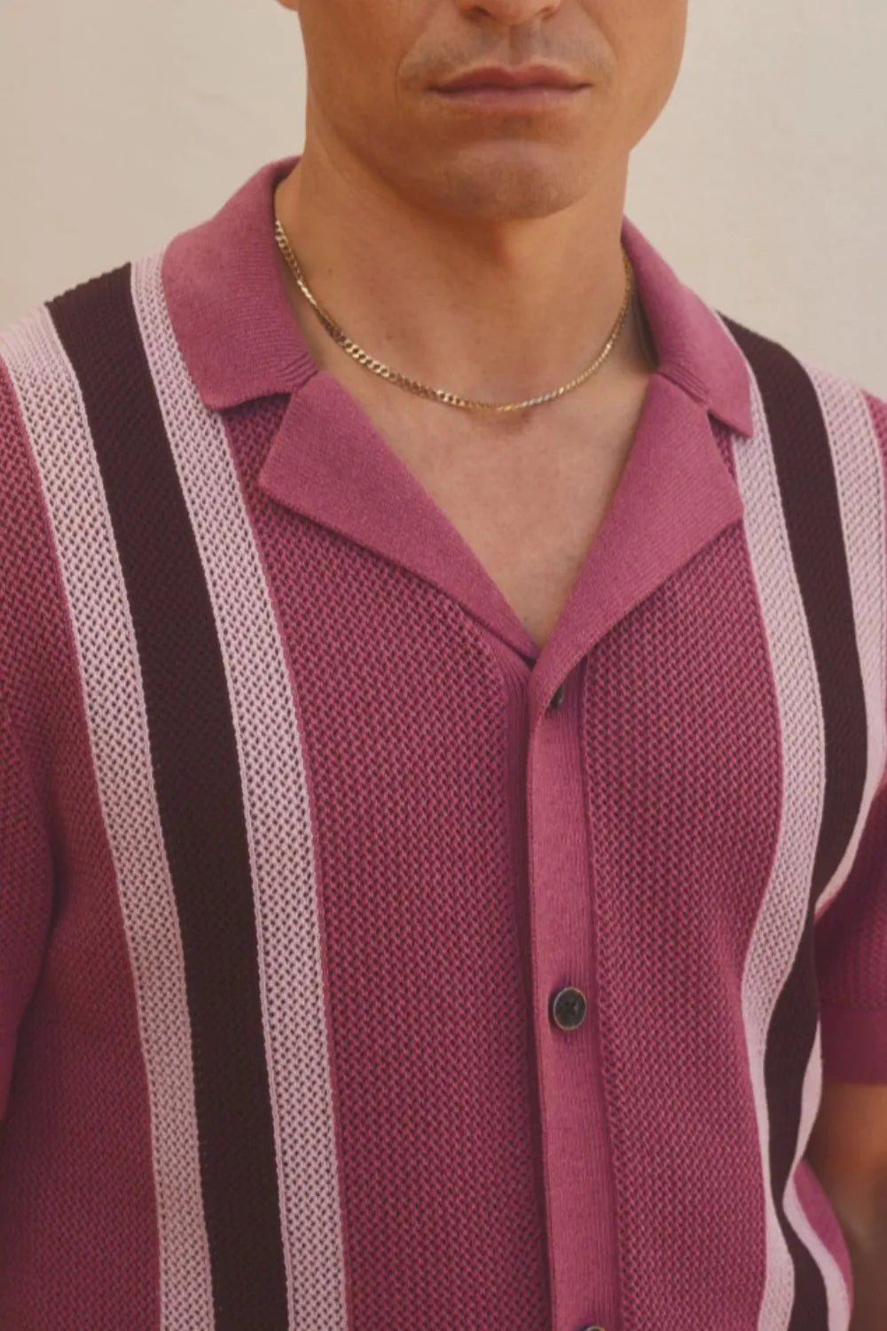 Striped knit polo shirt in red-violet with button front and spread collar.
