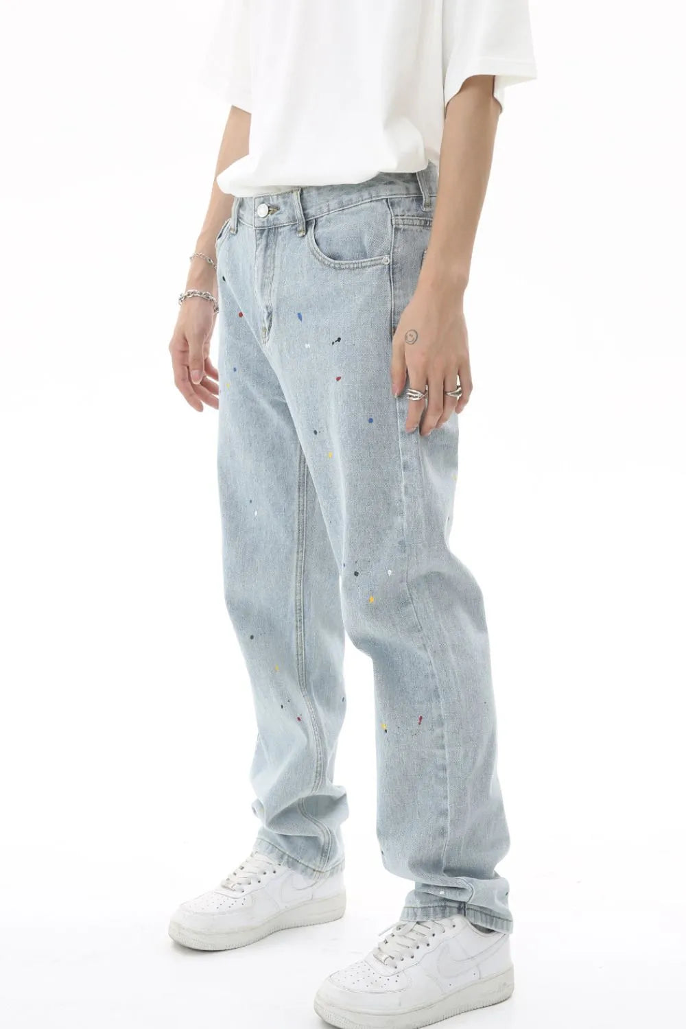 Light wash denim trousers with colorful paint splatters and a relaxed fit.