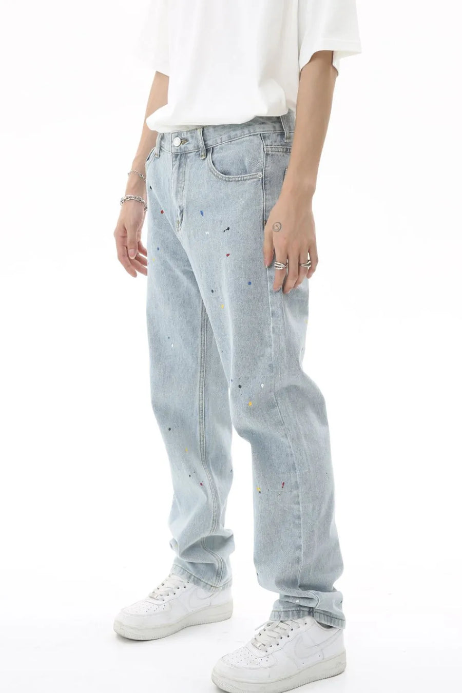 Light wash denim trousers with colorful paint splatters and a relaxed fit.