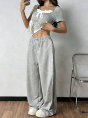 Grey tie front cropped top with white trim and drawstring wide-leg pants.