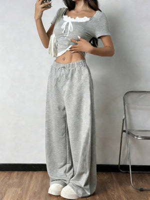 Grey tie front cropped top with white trim and drawstring wide-leg pants.