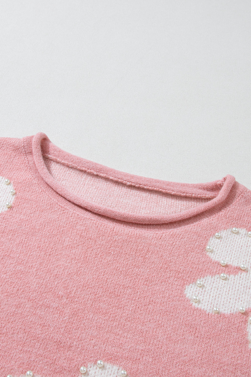 Blush pink knit sweater with pearl-embellished floral details and crew neck.