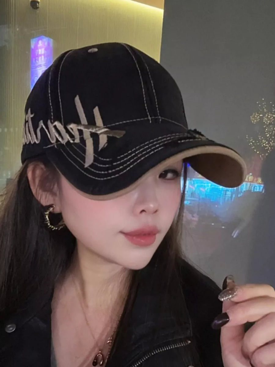 Black cotton baseball cap with stylized white embroidery and contrast stitching.