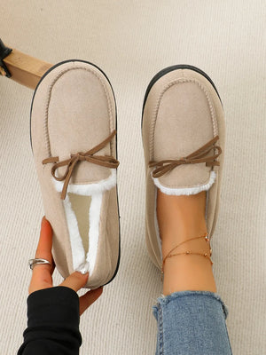 Caramel suede moccasin slippers with white faux fur lining and bow detail.