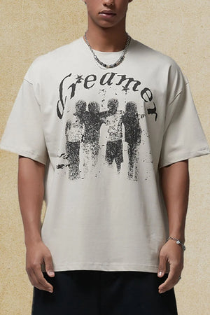 Ivory oversized graphic tee with distressed "Dreamer" text and a silhouette of four figures.