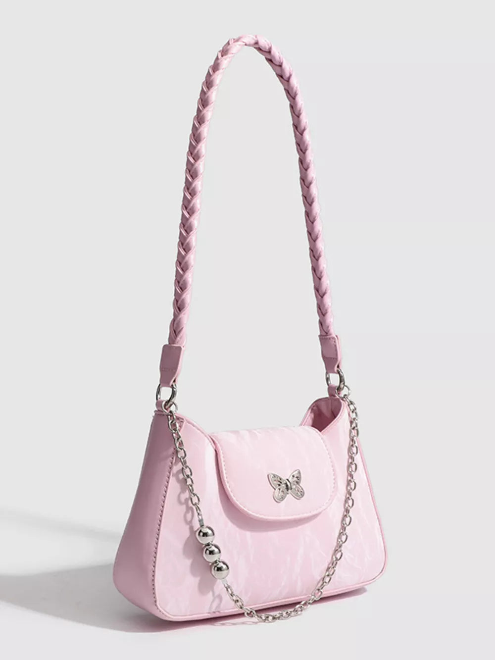 Pink shoulder bag with braided strap, butterfly charm, and silver chain detail.