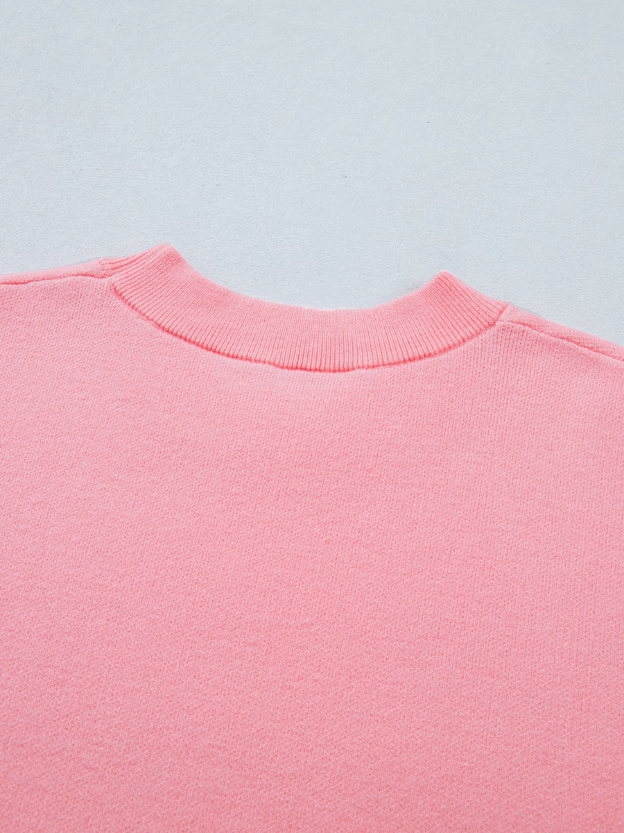 Pink knit top with ribbed mock neck and scalloped hem detail.
