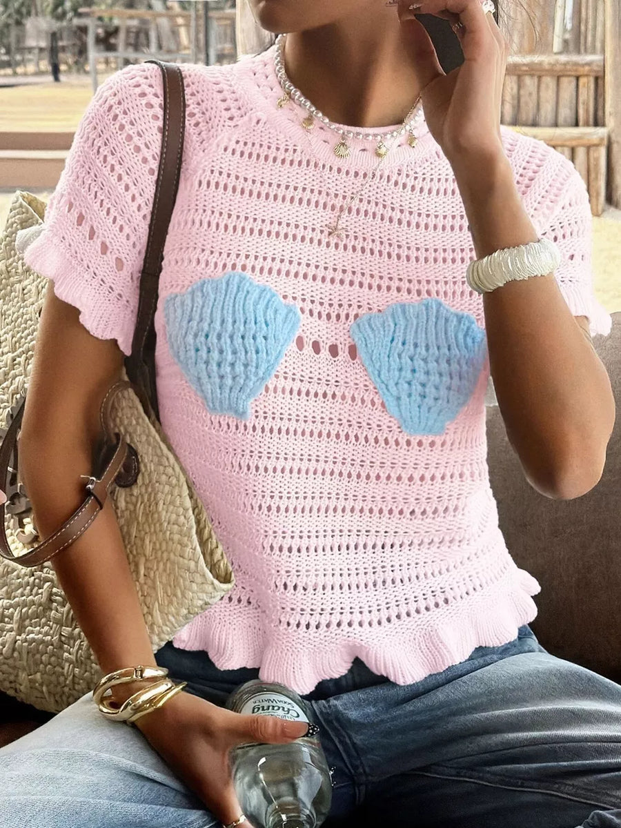 Pink knit top with ruffled hem and seashell appliqués, short sleeves, crew neck.