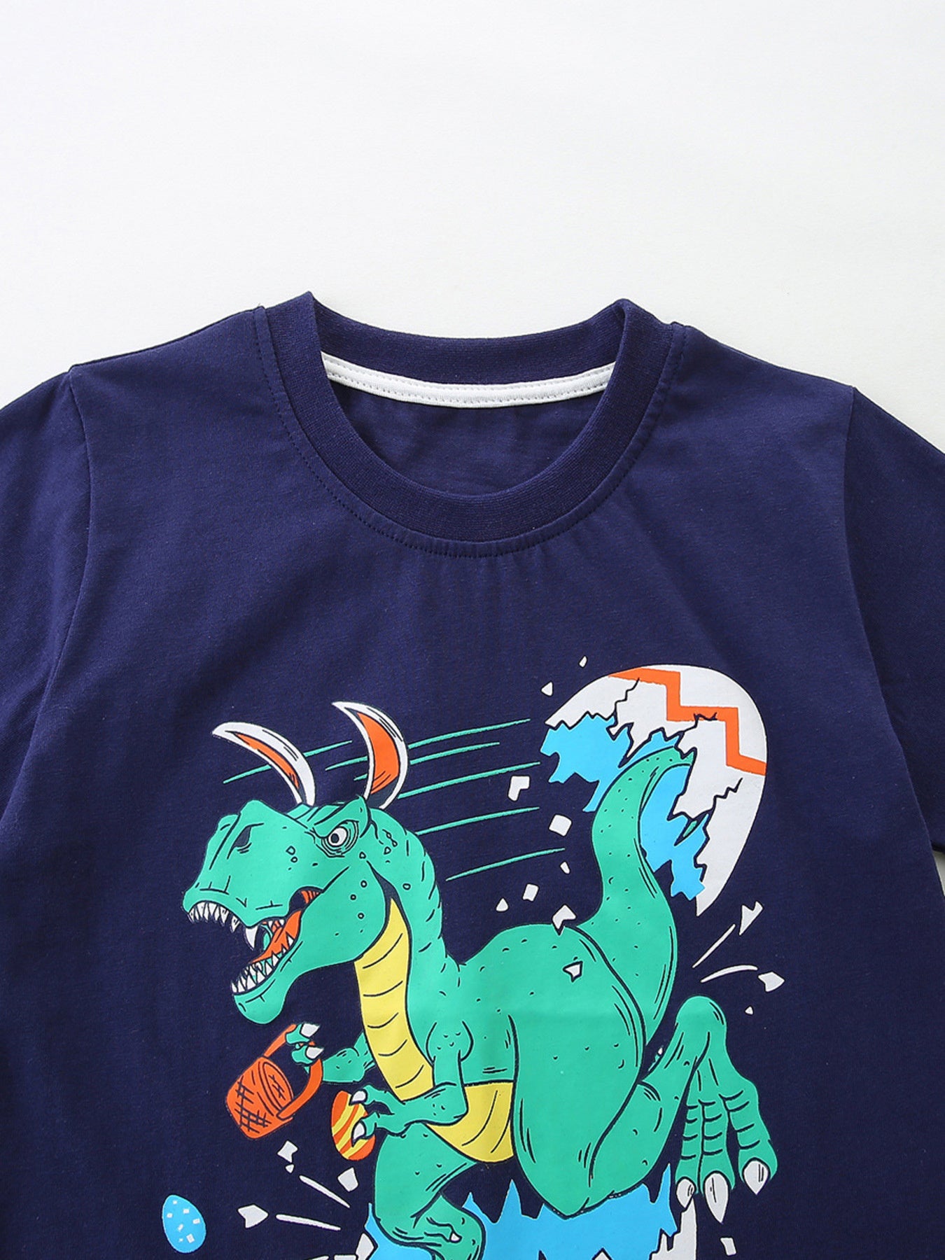 Navy cotton t-shirt with a graphic of a green dinosaur hatching from an egg.
