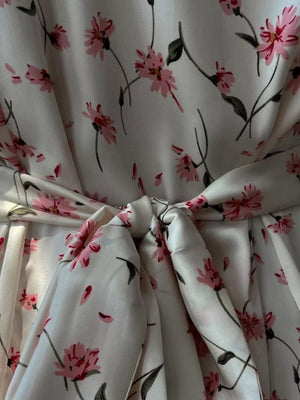 Dress with pink floral print on white satin, featuring a self-tie sash at the waist.