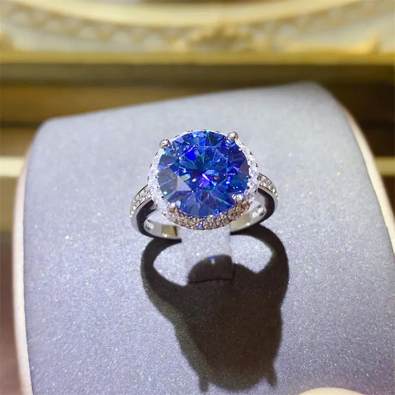 Silver halo cocktail ring with a large blue sapphire and small clear stones.