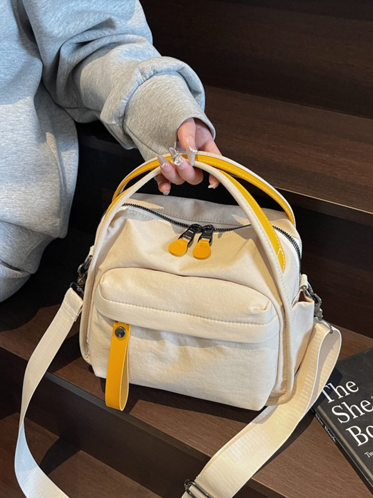 Cream canvas crossbody bag with yellow accents and decorative pull tab.