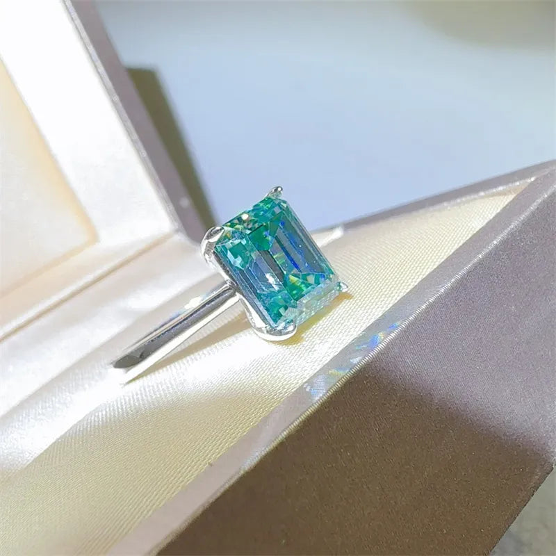 Emerald cut teal moissanite ring in silver with a classic band.