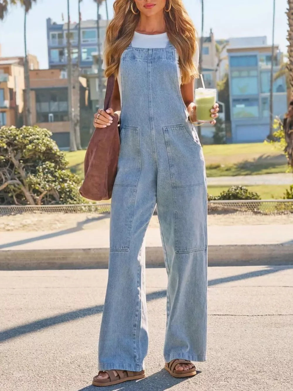 Light wash denim overalls with wide legs and utility pockets, worn with a white tee.
