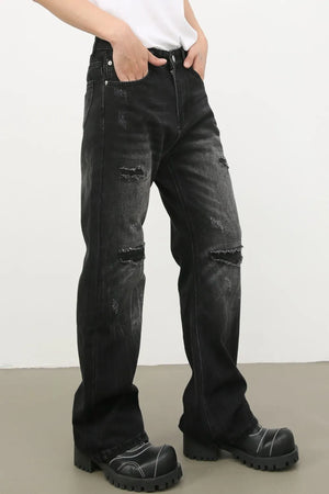 Distressed dark wash flare jeans with bleach details and ripped knees.