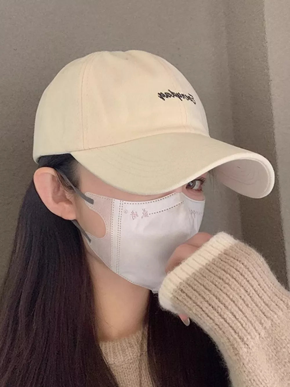 Beige cotton baseball cap with black embroidery detail.