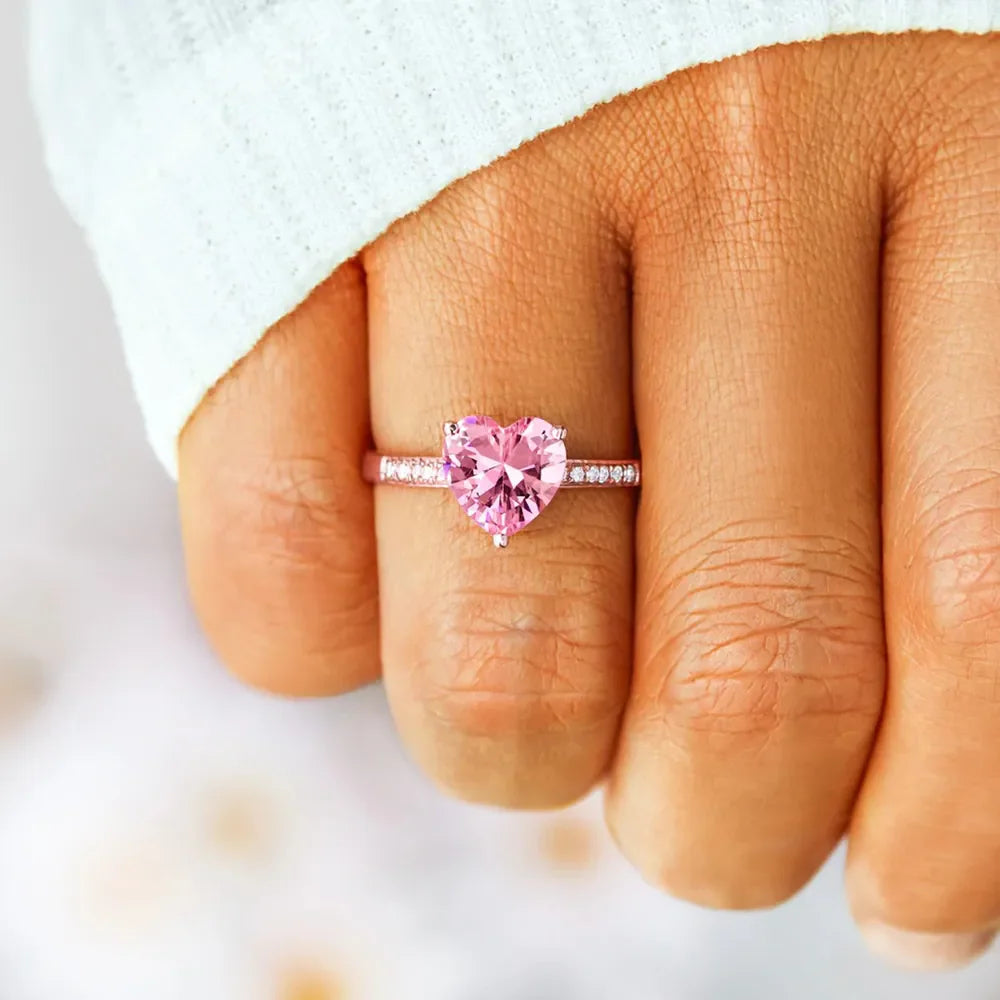 Rose gold ring with a pink heart cut pavé stone and small clear stones on the band.