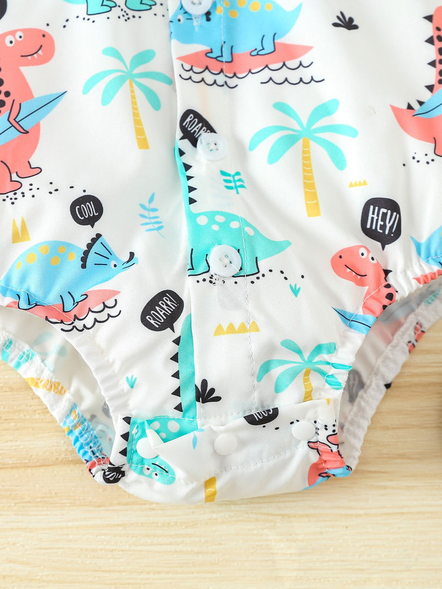 White cotton baby bodysuit with colorful dinosaur print, palm trees, and speech bubbles.