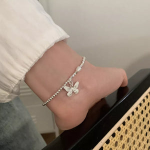 white bracelet featuring butterfly charm and butterfly motif