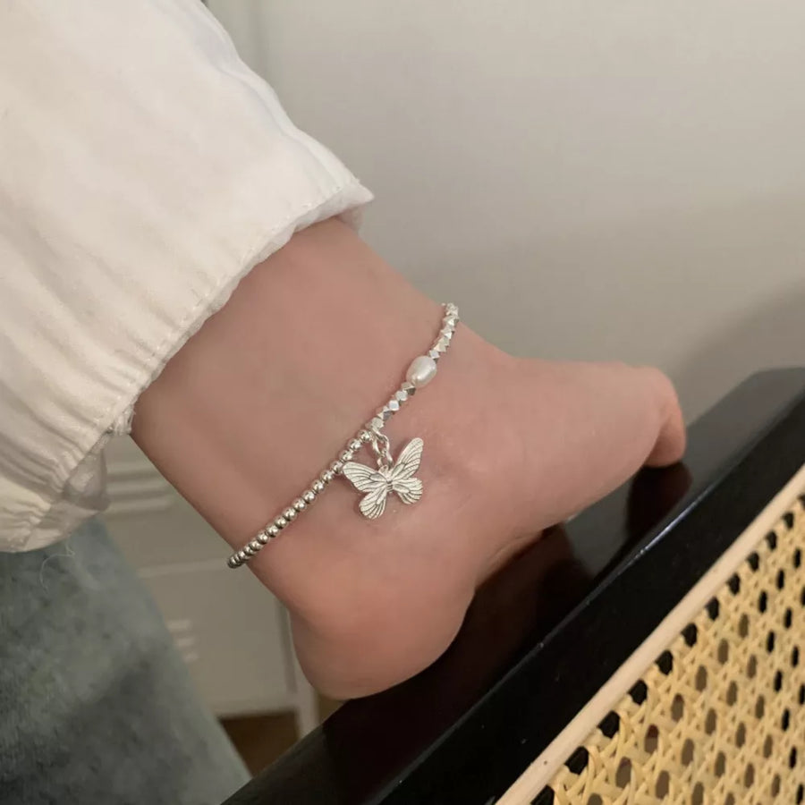 white bracelet featuring butterfly charm and butterfly motif