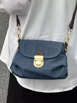 Mini denim shoulder bag with gold turn-lock closure and adjustable strap.
