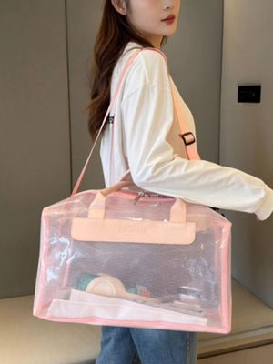 Chic transparent PVC travel bag in pink with mesh detail and pink straps, holding toiletries.