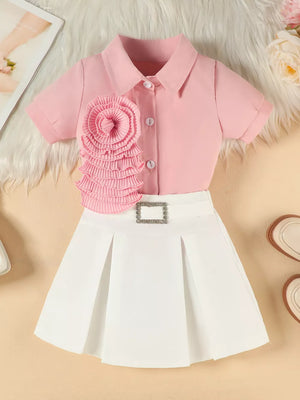 Pink floral appliqué shirt with white pleated skirt and decorative buckle for toddlers.