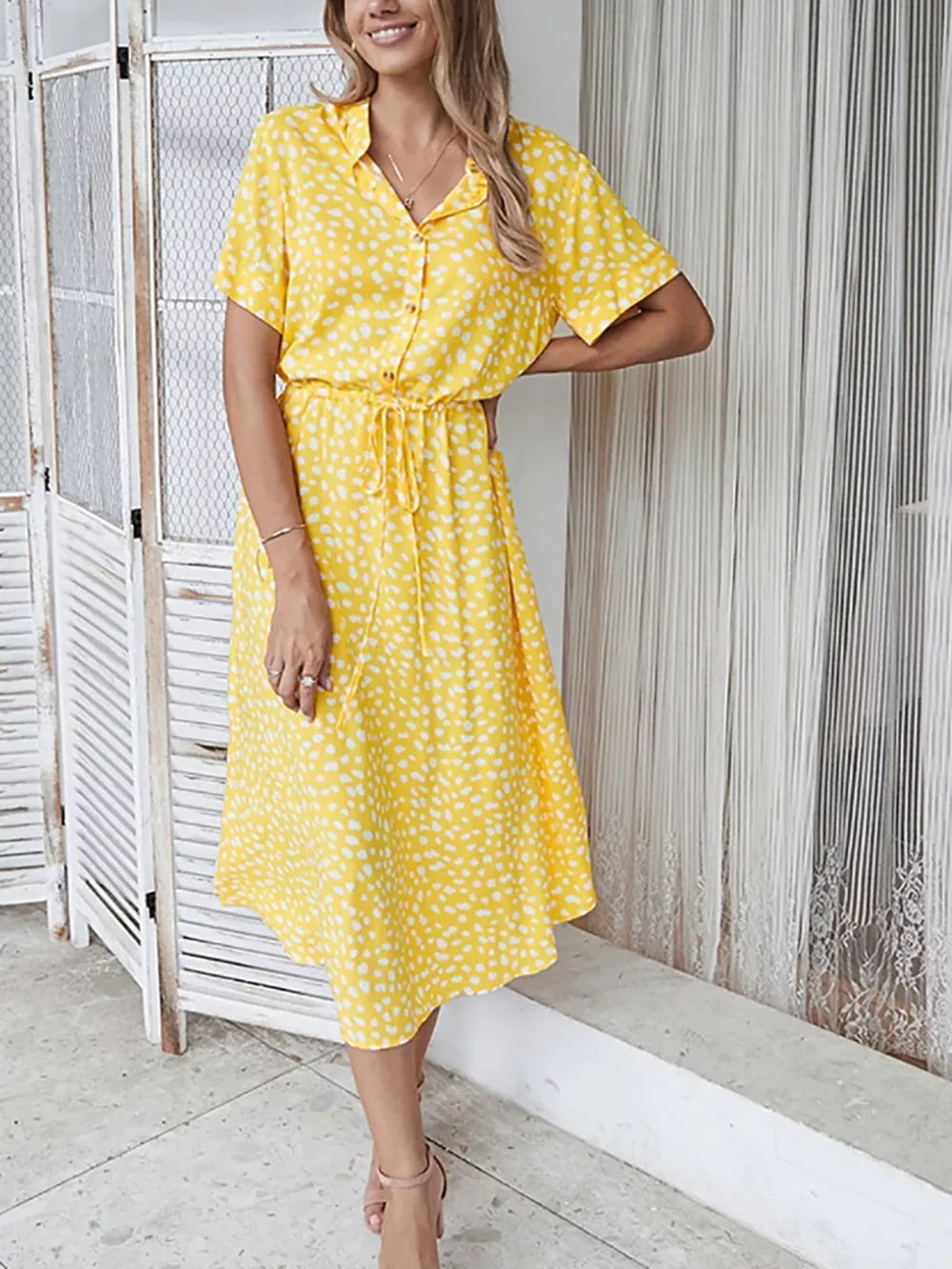 Yellow polka dot midi dress with tie waist, short sleeves, and collared neckline.