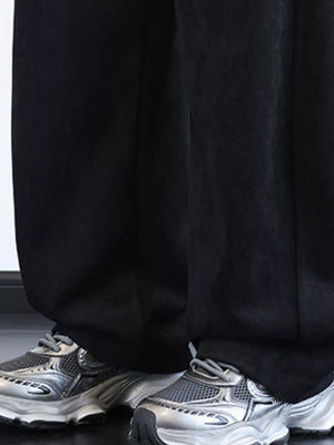 Men's black wide-leg sweatpants with pockets, styled with sneakers.
