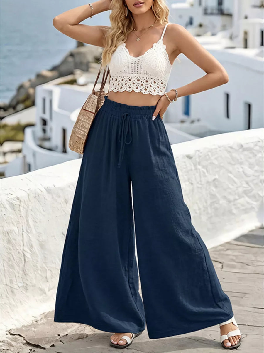 Navy linen wide-leg pants with drawstring waist and ruffled hem, styled with a white lace crop top.