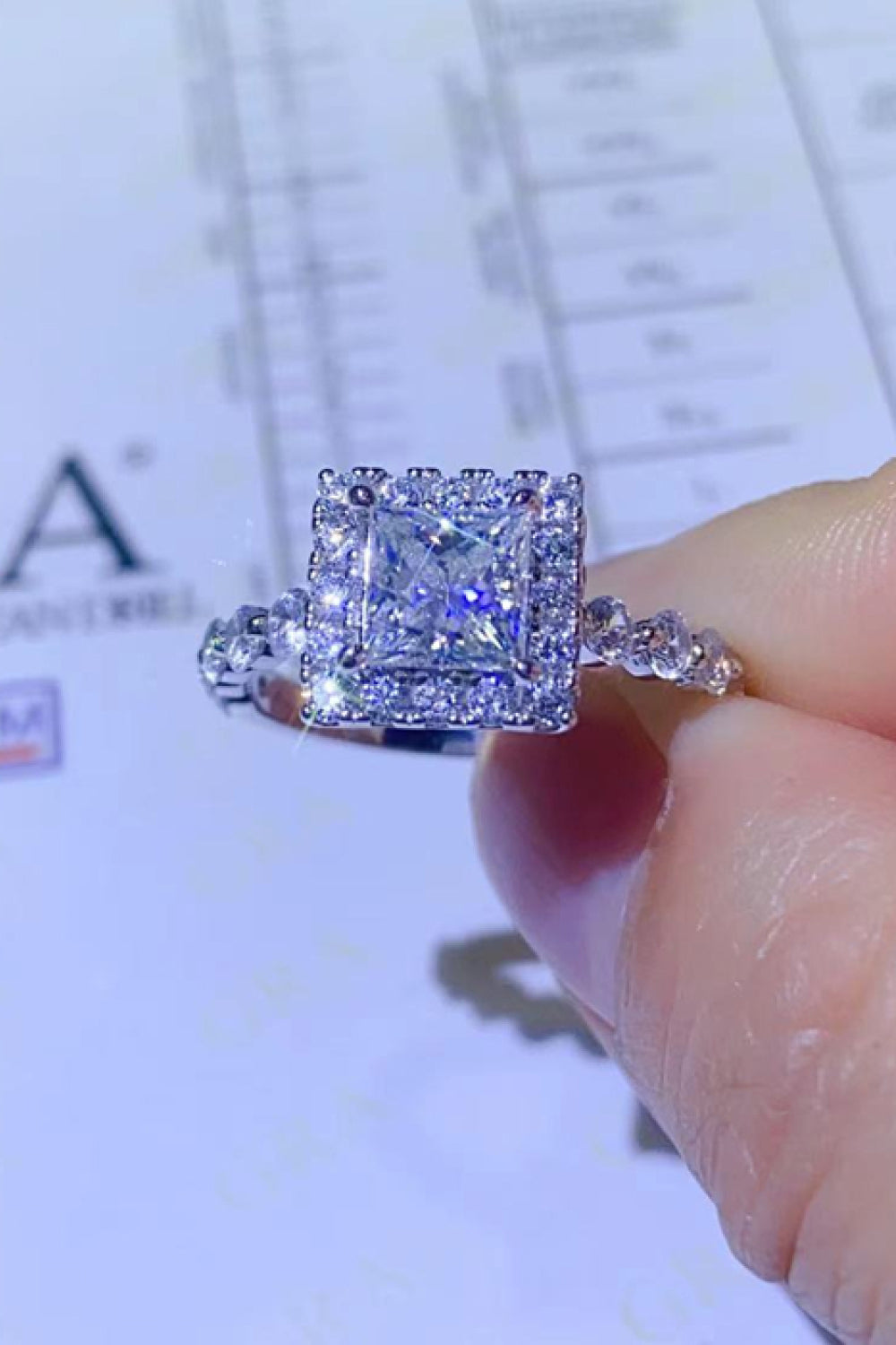 White moissanite engagement ring with cushion cut center stone and halo setting.