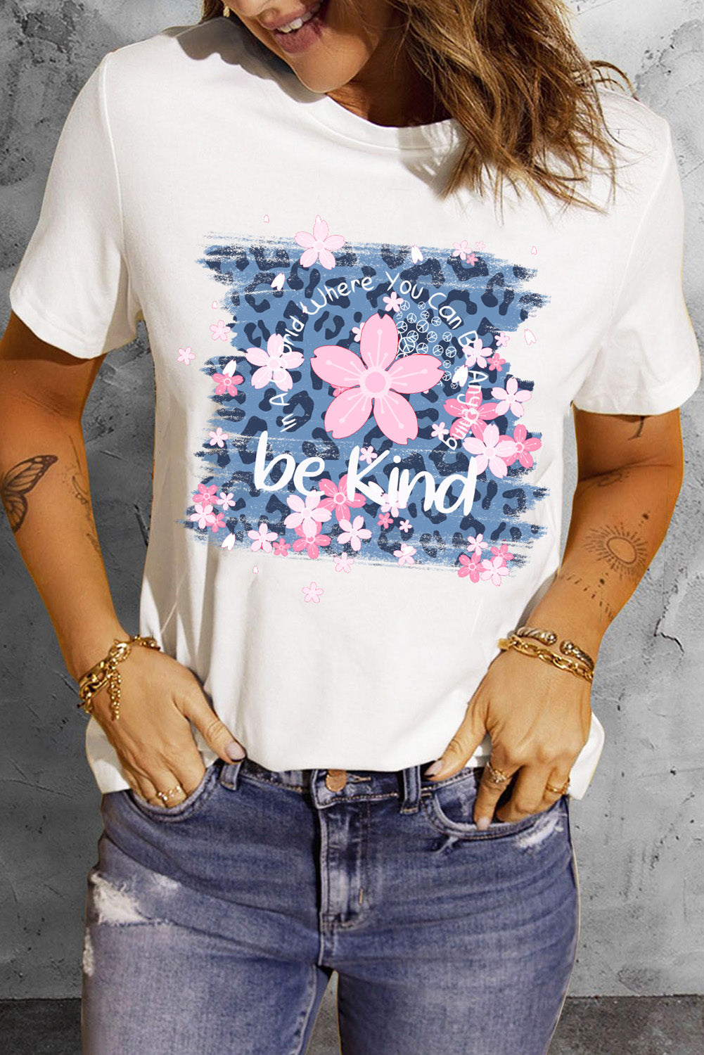White graphic tee with floral accents and "be kind" text