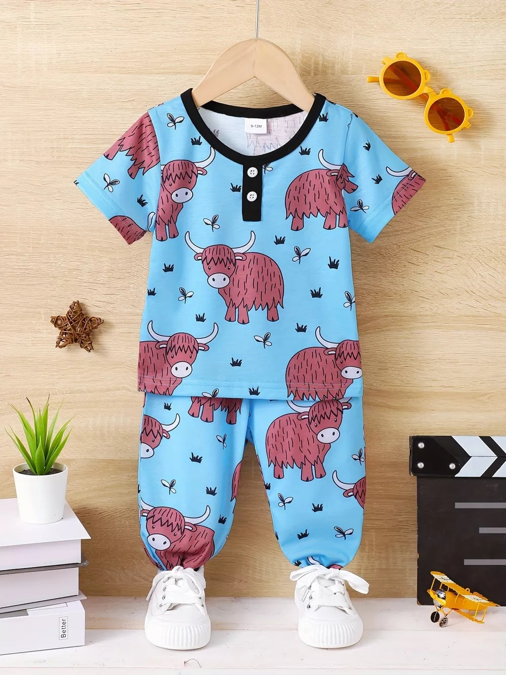 Baby pajama set with highland cow print, blue, short sleeves, button neck, elastic cuffs