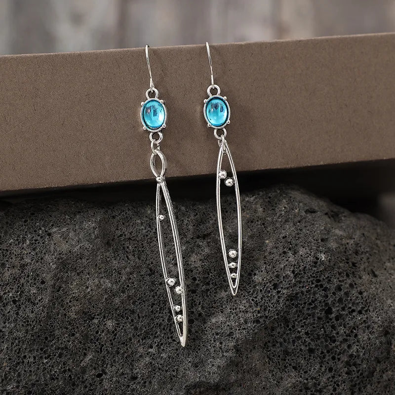 Silver dangle earrings with azure oval gems and elongated leaf-shaped drops.